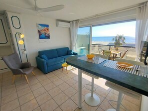 Ein Wohnbereich mit einer Couch, einem Esstisch und Meerblick.