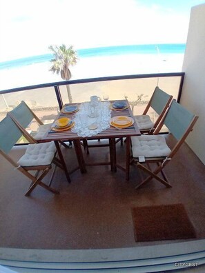Enjoy meals with a view of the beach and palm trees from this dining area with a table for four.