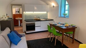 A compact kitchen with a dining area, a sofa, and a window with a plant. - Medieval Mountain Oasis With a Private G (Castelbianco)