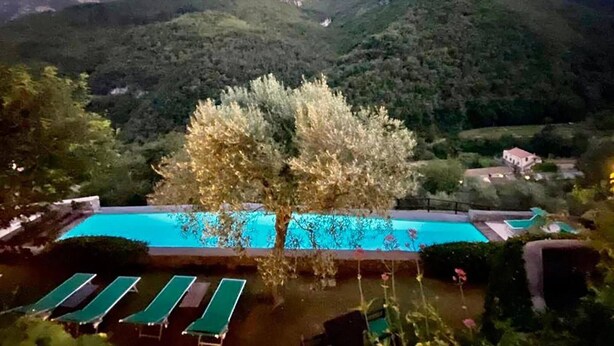 A pool area with lounge chairs, a tree, and a mountain backdrop. - Medieval Mountain Oasis With a Private G (Castelbianco)