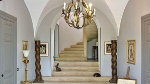 Una imponente escalera con un candelabro, obras de arte enmarcadas y un pequeño conejo en los peldaños.