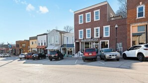A street view with parked cars, a brick building labeled 'THE EXCHANGE', and various storefronts. - Park House on Main (Parkville)