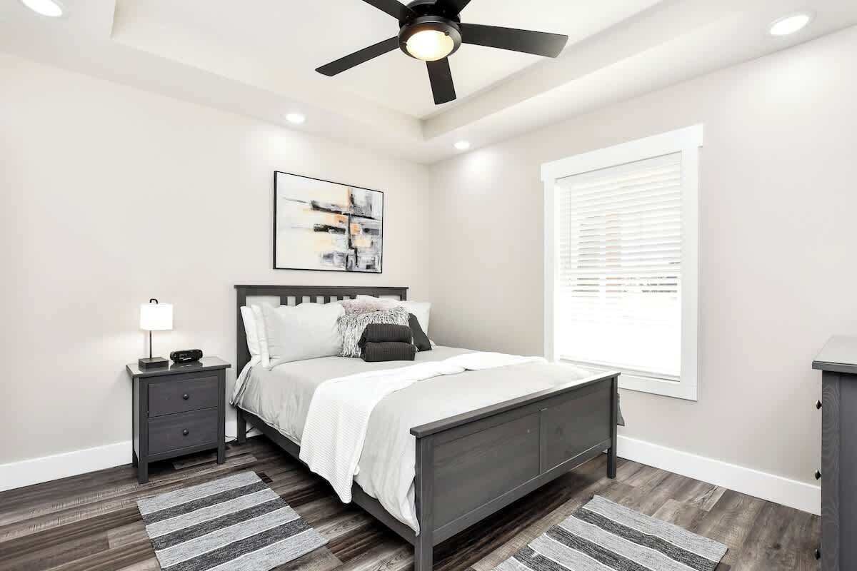 Rest in a bright bedroom with bedside lighting and a ceiling fan overhead.