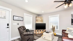 A modern living room with a leather sofa, a television, and a ceiling fan.