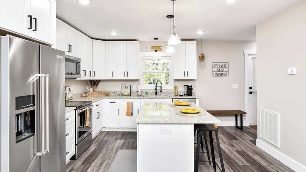 A modern kitchen with white cabinets, stainless steel appliances, and a central island with stools.