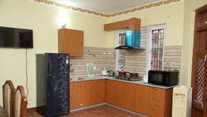 Una cocina con armarios de madera, un refrigerador, un microondas y un dispensador de agua.