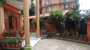 Un patio con plantas en macetas, un banco y una entrada decorativa.