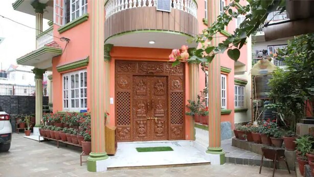 Una casa con una puerta principal grande y decorativa, plantas en macetas y un pequeño porche.