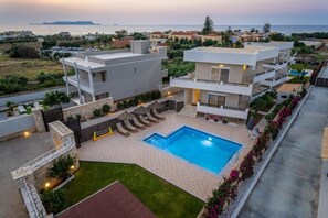 Una casa moderna de dos pisos con piscina, jardín y vistas al mar.