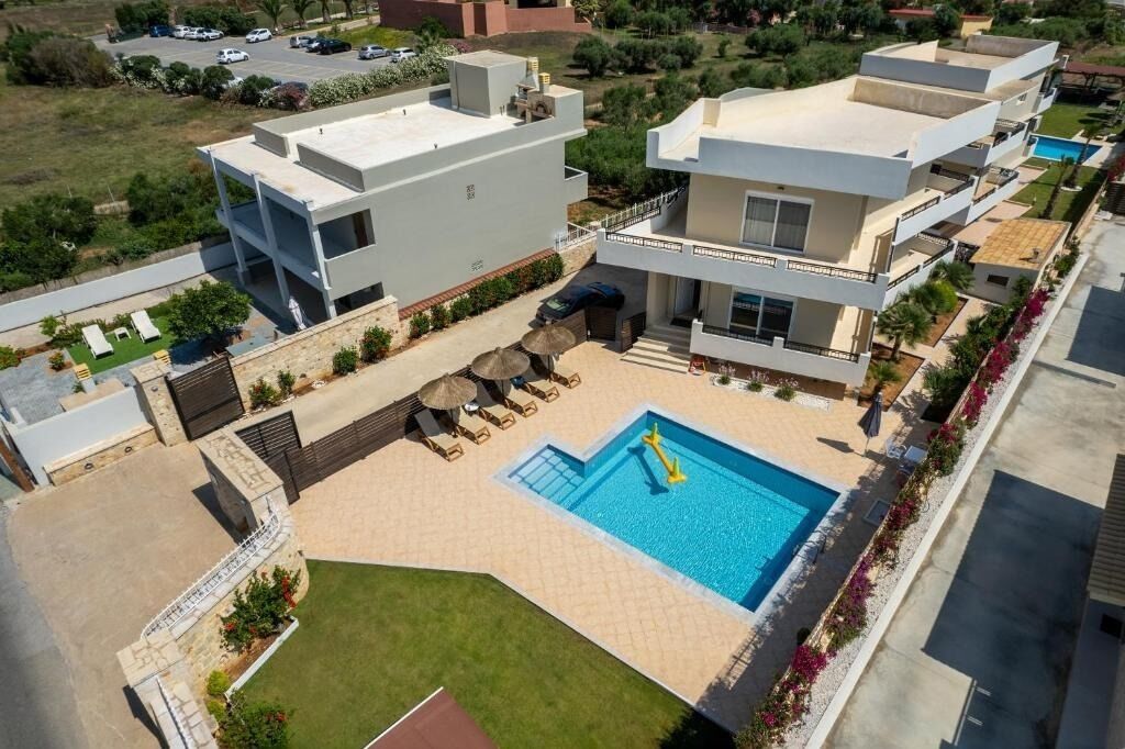 A modern residential building with a rooftop pool, outdoor seating, and a well-maintained garden.