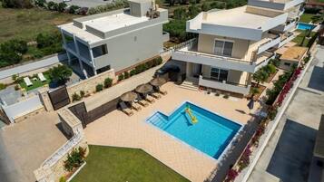 A modern residential building with a rooftop pool, outdoor seating, and a well-maintained garden.