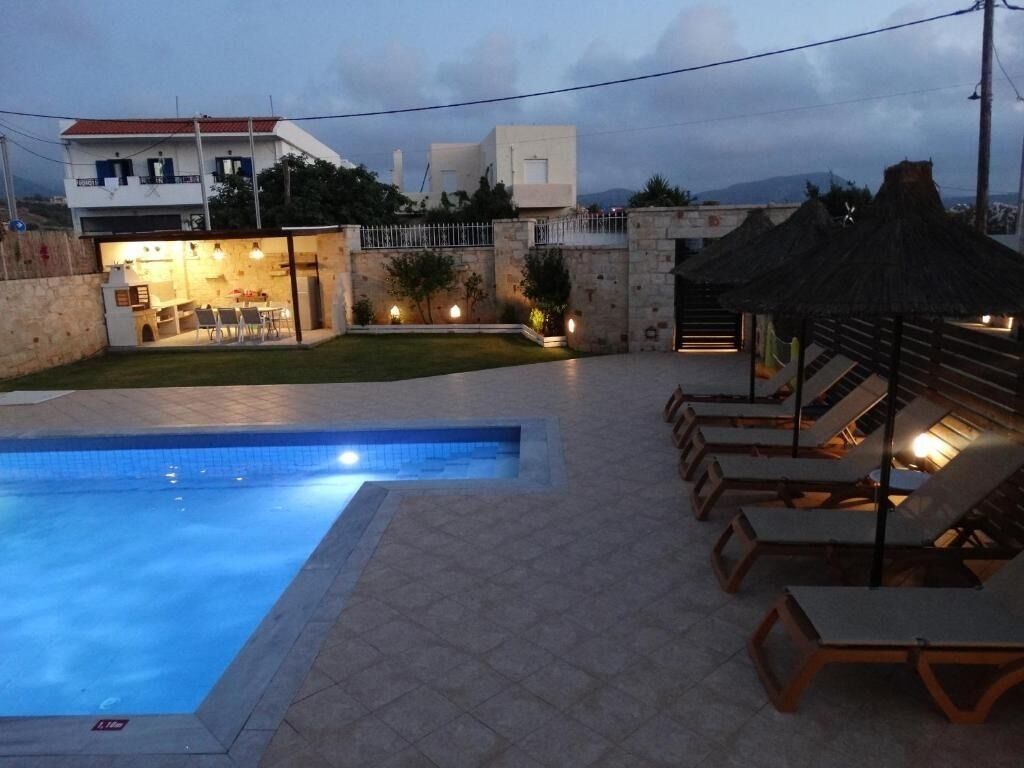 Una piscina con sillones de descanso y zona de comedor.