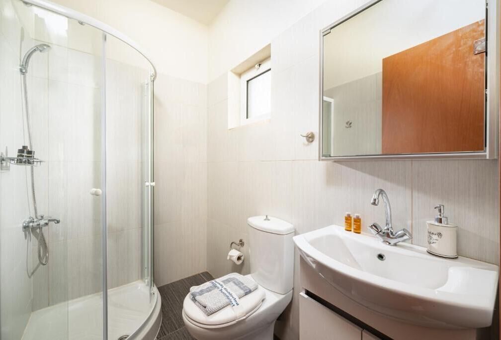 Une salle de bain avec une douche à parois de verre, des toilettes, un lavabo et un miroir au-dessus du lavabo.