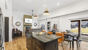 Una cocina moderna con una isla central, suelo de madera e iluminación colgante.
