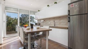 A modern kitchen with a stainless steel refrigerator, a wooden countertop, and a dining area with a table and chairs. - Holiday home with terrace and pool (Poljane)