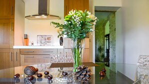 A modern kitchen with wooden cabinets, a glass dining table, and a vase with flowers. - 1 bedroom nice home in Carnas (Carnas)