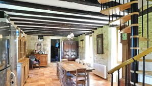 Una cocina amplia con una gran mesa de madera y sillas, un refrigerador y una escalera con barandilla.