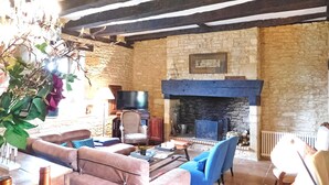 Una habitación rústica con paredes de piedra, chimenea, sofás de cuero y televisión.