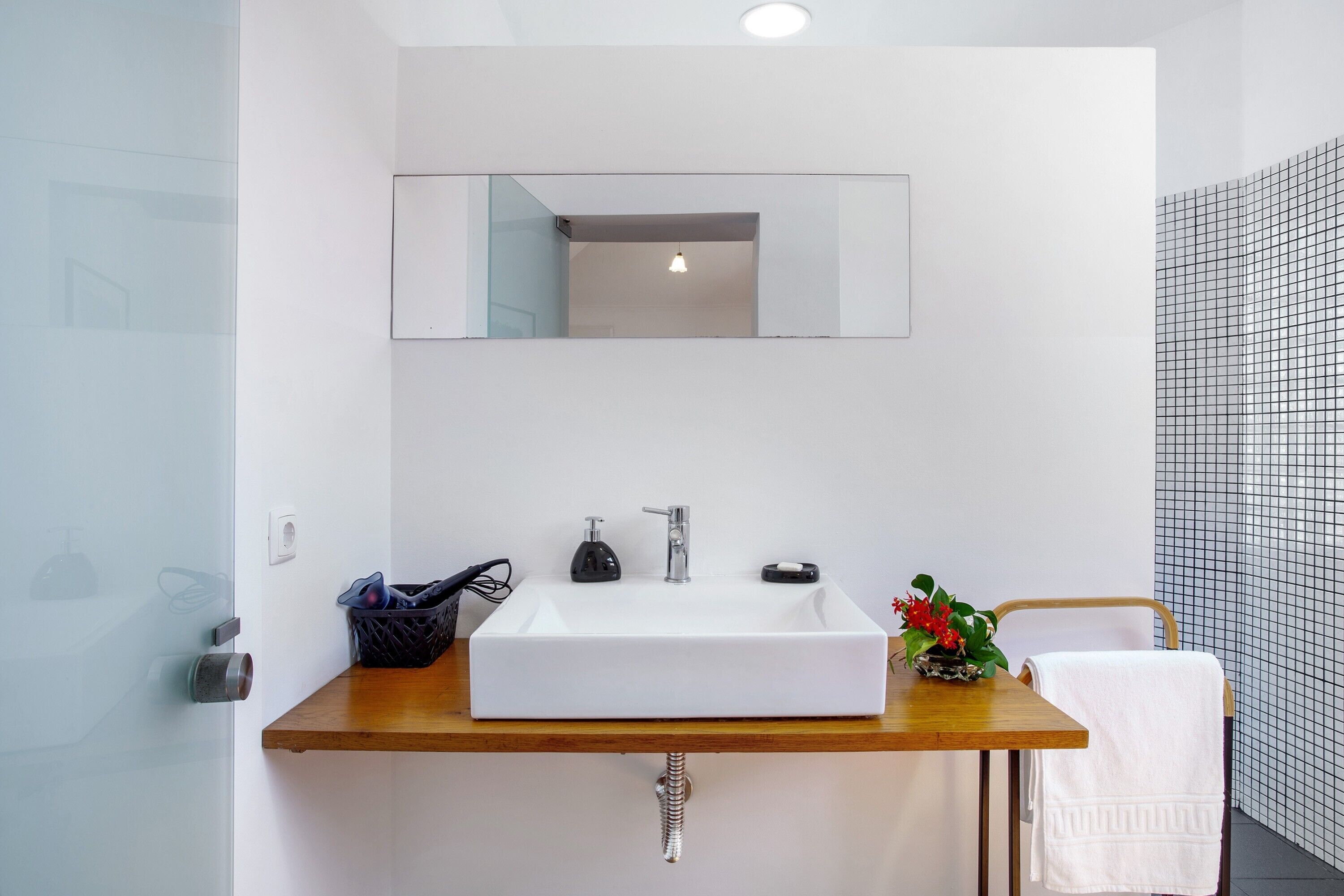 Un bagno con lavandino bianco, specchio e porta asciugamani.