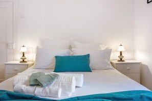 A neatly made bed with white and teal bedding, two bedside lamps, and a teal throw blanket. - Holiday Home 'Mother's House' with Sea View, Private Terrace and Wi-Fi (Calheta)