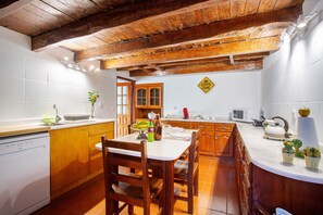 A kitchen with wooden cabinets, a dining table, and a coffee zone sign. - Holiday Home 'Mother's House' with Sea View, Private Terrace and Wi-Fi (Calheta)