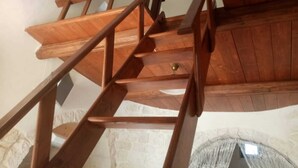 A wooden staircase with a handrail, leading to a room with a stone wall and a window. - Apartment 'Trullo Fico' with Shared Pool, Shared Terrace and Wi-Fi (Martina Franca)