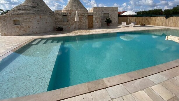 A swimming pool with stone buildings in the background. - Apartment 'Trullo Fico' with Shared Pool, Shared Terrace and Wi-Fi (Martina Franca)