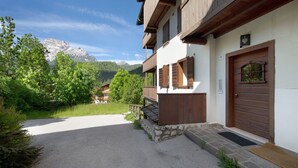 A building with a stone foundation, wooden balconies, and a door with a metal gate. - Apartment 'Villa Cleila Blu D' with Mountain View, Shared Garden and Balcony (San Vito di Cadore)