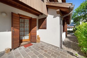 A building with a wooden door, a red mat, and a stone-paved entrance. - Apartment 'Villa Cleila Blu D' with Mountain View, Shared Garden and Balcony (San Vito di Cadore)