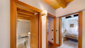A hallway with wooden doors leading to a bathroom and a bedroom. - Apartment 'Villa Cleila Blu D' with Mountain View, Shared Garden and Balcony (San Vito di Cadore)