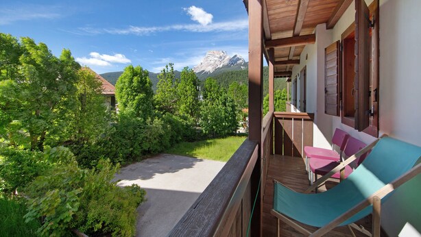 A balcony with a view of a mountain, surrounded by greenery. - Apartment 'Villa Cleila Blu D' with Mountain View, Shared Garden and Balcony (San Vito di Cadore)