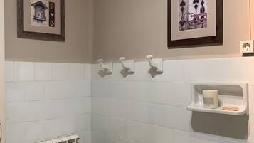 Un baño con un radiador, una bolsa para la ropa, un perchero y dos cuadros en la pared.