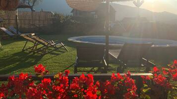 Un patio trasero con piscina, sillas de descanso y una lámpara colgante.
