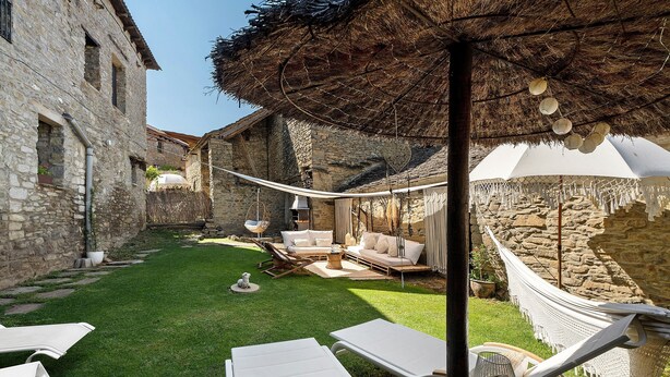 Un patio con edificios de piedra, una hamaca y mobiliario exterior.