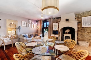 A cozy living room with wicker furniture, a fireplace, and a stone wall.