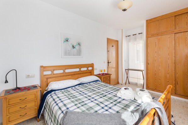 A bedroom with a wooden bed, a nightstand with a lamp, a wardrobe, and a painting on the wall.