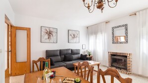 Een eethoek met een houten tafel, stoelen, een bank, een open haard en kunstwerken aan de wanden.