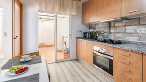 Een moderne keuken met houten kastjes, een granieten aanrechtblad, een ingebouwde oven en een schuifdeur naar een wasruimte.