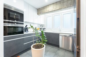 Une cuisine moderne équipée d’appareils électroménagers en acier inoxydable, agrémentée d’une plante en pot et d’un lave-vaisselle.