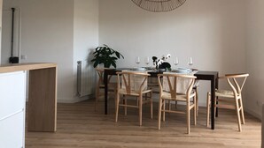 A dining area with a wooden table, chairs, a hanging light fixture, and a potted plant. - Apartment 'Apartament Creu De Sant Pol' with Sea View and Wi-Fi (Sant Feliu de Guíxols)