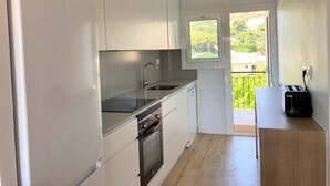 A compact kitchen with white cabinets, a stainless steel sink, and a built-in oven. - Apartment 'Apartament Creu De Sant Pol' with Sea View and Wi-Fi (Sant Feliu de Guíxols)