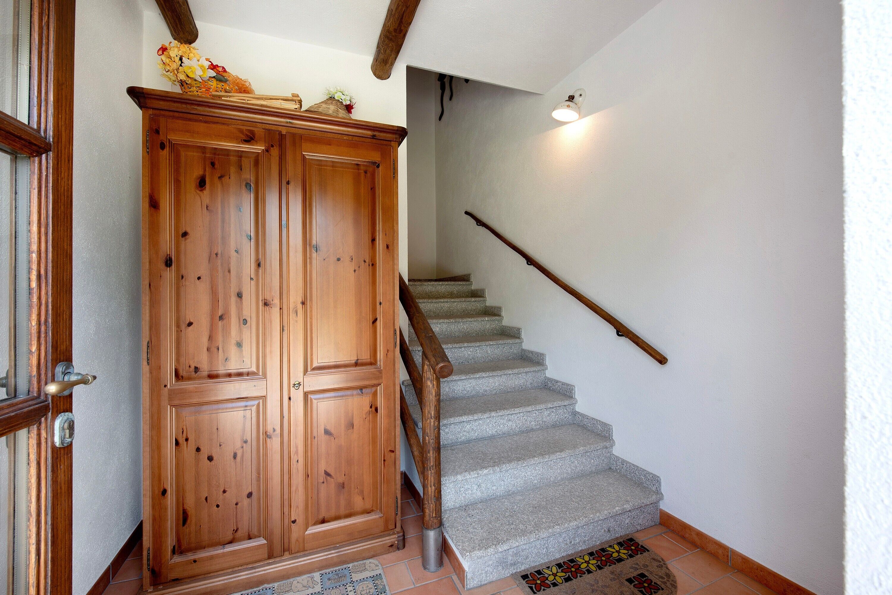 Ein Holzschrank, eine Treppe mit Handlauf und ein Teppich auf dem Boden.