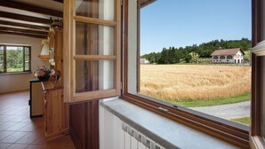 Una habitación con un ventanal grande, armarios de madera y vistas a un campo y edificios.