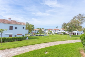 Un quartier résidentiel avec des bâtiments blancs, une pelouse bien entretenue et un chemin pavé.
