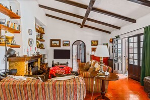 A cozy living room with a fireplace, striped sofas, a table, and a bookshelf. - Holiday Home 'Vila Das Manas' with Private Pool, Private Garden and Wi-Fi (Verdizela)