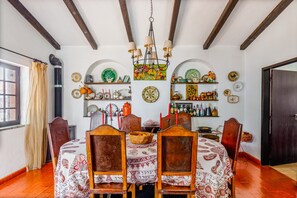 A dining room with a wooden table and chairs, a chandelier, and various decorative plates on the walls. - Holiday Home 'Vila Das Manas' with Private Pool, Private Garden and Wi-Fi (Verdizela)