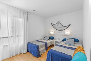 A room with two beds, a white ceiling, and a wall-mounted light fixture.