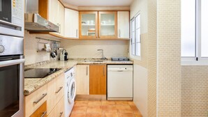 A compact kitchen with a dishwasher, oven, and microwave. - Apartment 'Cristina Center' with Balcony, Wi-Fi and Air Conditioning (València)