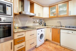 A kitchen with a microwave, oven, washing machine, and dishwasher.