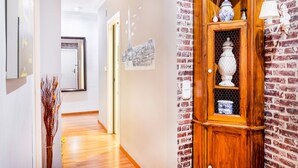 A hallway with a wooden cabinet, a wall-mounted lamp, and a framed cityscape. - Apartment 'Cristina Center' with Balcony, Wi-Fi and Air Conditioning (València)
